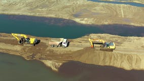 Aerial view of two yellow excavators with truck working in quarries site. Heavy equipment is grading the land. Concept