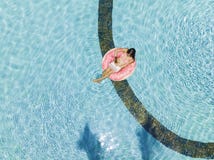 Aerial view of a young brunette woman swimming on an inflatable big donut with a laptop in a transparent turquoise pool. stock images Aerial view of a young brunette woman swimming on an inflatable big donut with a laptop in a transparent turquoise pool. stock images