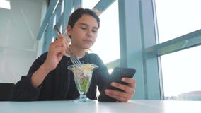 Aeroporto che aspetta un volo in aereo La ragazza teenager mangia l'insalata e guarda lo smartphone Internet in uno stile di vita archivi video Aeroporto che aspetta un volo in aereo La ragazza teenager mangia l'insalata e guarda lo smartphone Internet in uno stile di vita archivi video