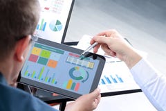 Affärskollegor som arbetar och analyserar finansiella diagram på en digital minnestavla royaltyfri foto Affärskollegor som arbetar och analyserar finansiella diagram på en digital minnestavla royaltyfri foto