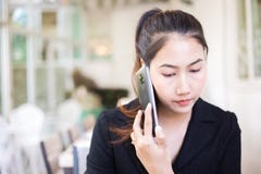 Affärskvinnor som konsulterar partnern vid telefonen, medan sitta i coffee shop fotografering för bildbyråer Affärskvinnor som konsulterar partnern vid telefonen, medan sitta i coffee shop fotografering för bildbyråer