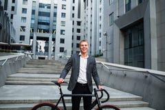 Affärsman med cykeln som upp går trappan på bakgrunden av affärsmitt royaltyfri fotografi Affärsman med cykeln som upp går trappan på bakgrunden av affärsmitt royaltyfri fotografi