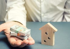 Affärsmannen rymmer dollar i händer nära trähus som white för pussel för investering för hus för gods för bakgrundsbegreppsdollar arkivbild Affärsmannen rymmer dollar i händer nära trähus som white för pussel för investering för hus för gods för bakgrundsbegreppsdollar arkivbild