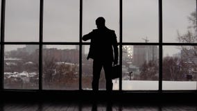 Affärsmannen ser tid på armbandsuret i regeringsställning nära fönster Affärsmannen ser tid på armbandsuret i regeringsställning nära fönster