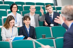 AffärsmanRaising Hand While kollega som ger presentation arkivbild AffärsmanRaising Hand While kollega som ger presentation arkivbild