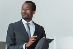 African american businessman sitting on chair in office and looking away Stock Photography African american businessman sitting on chair in office and looking away Stock Photography