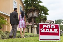 African American Couple Beside House For Sale Sign