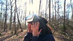 African American girl teenager female young woman using virtual reality VR headset in a forest woodland environment stock video African American girl teenager female young woman using virtual reality VR headset in a forest woodland environment stock video