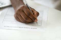 African american man filling employment application form, close