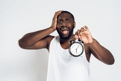 African American man holds head with alarm clock royalty free stock images African American man holds head with alarm clock royalty free stock images