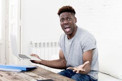 African american man sitting at home living room working with laptop computer and paperwork Royalty Free Stock Photo African american man sitting at home living room working with laptop computer and paperwork Royalty Free Stock Photo