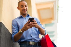 African American Man Text Messaging On Phone With Shopping Bags royalty free stock images African American Man Text Messaging On Phone With Shopping Bags royalty free stock images
