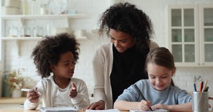 African mother, babysitter checking homework helping diverse ethnicity children