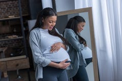 african american pregnant woman looking at her belly while standing royalty free stock image african american pregnant woman looking at her belly while standing royalty free stock image