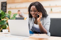 African american woman talking on smartphone while using laptop in cafe royalty free stock photo African american woman talking on smartphone while using laptop in cafe royalty free stock photo
