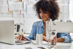 African-American Woman Uses Laptop At Workplace With Sewing Machine Royalty Free Stock Photo