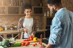 African american young woman looking at boyfriend while cooking salad Stock Photography African american young woman looking at boyfriend while cooking salad Stock Photography