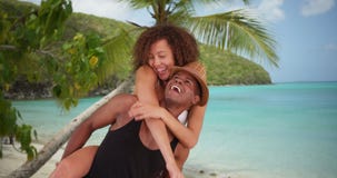 Afrikanska amerikanen som millennial par ger sig rider på ryggen, vid stranden royaltyfri fotografi Afrikanska amerikanen som millennial par ger sig rider på ryggen, vid stranden royaltyfri fotografi