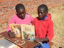 Afrikanska barn som läser en bibelberättelsebok fotografering för bildbyråer Afrikanska barn som läser en bibelberättelsebok fotografering för bildbyråer