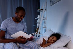 Afroamerikanervater-Lesebuch für schlafende Tochter stockbild Afroamerikanervater-Lesebuch für schlafende Tochter stockbild