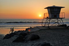Runners running along the Oceanside beach past a lifeguard tower as the sun sets. royalty free stock photography Runners running along the Oceanside beach past a lifeguard tower as the sun sets. royalty free stock photography