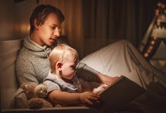 Aftonfamiljläsning fadern läser barn bok, innan att gå arkivfoton Aftonfamiljläsning fadern läser barn bok, innan att gå arkivfoton