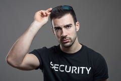Agent de sécurité dur enlevant des lunettes de soleil avec le regard fixe intense à l'appareil-photo Photos libres de droits Agent de sécurité dur enlevant des lunettes de soleil avec le regard fixe intense à l'appareil-photo Photos libres de droits