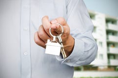 Agent immobilier tenant des clés sur la nouvelle maison photographie stock Agent immobilier tenant des clés sur la nouvelle maison photographie stock