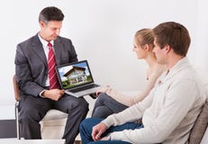 Agente immobiliare che mostra computer portatile alle coppie fotografia stock libera da diritti Agente immobiliare che mostra computer portatile alle coppie fotografia stock libera da diritti