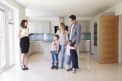 Agente immobiliare che mostra giovane famiglia intorno alla proprietà da vendere immagine stock Agente immobiliare che mostra giovane famiglia intorno alla proprietà da vendere immagine stock