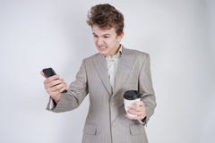 Aggressiver kaukasischer Jugendlicher schreit in das intelligente Telefon und h?lt einen Papiertasse kaffee in seiner Hand Studen stockfotos Aggressiver kaukasischer Jugendlicher schreit in das intelligente Telefon und h?lt einen Papiertasse kaffee in seiner Hand Studen stockfotos