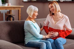 Aging happy beaming madam fondly palming her daughter baby bump stock image Aging happy beaming madam fondly palming her daughter baby bump stock image