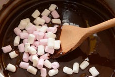 Agitando mini marshmallows no chocolate derretido imagens de stock Agitando mini marshmallows no chocolate derretido imagens de stock