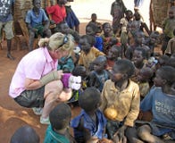 Aid worker brings hope to smiling African children in village Uganda stock image Aid worker brings hope to smiling African children in village Uganda stock image