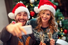 Aimez les couples ayant l'amusement et prenez les photos de Noël sur le mobile Image libre de droits Aimez les couples ayant l'amusement et prenez les photos de Noël sur le mobile Image libre de droits