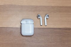 Airpods sans fil blancs sur le fond en bois avec la boîte de chargeur, foyer choisi photo stock Airpods sans fil blancs sur le fond en bois avec la boîte de chargeur, foyer choisi photo stock