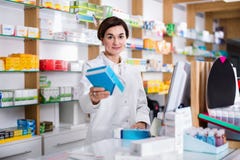 Ajuda de oferecimento do farmacêutico fêmea na escolha no contador no pharma fotos de stock Ajuda de oferecimento do farmacêutico fêmea na escolha no contador no pharma fotos de stock