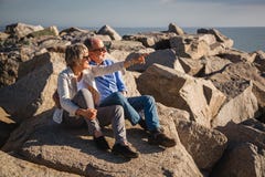 Aktive ?ltere Paare, die auf sonnige Felsen durch das Meer gehen stockbilder Aktive ?ltere Paare, die auf sonnige Felsen durch das Meer gehen stockbilder