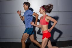 Aktywnej potomstwo pary jogging strona popiera kogoś w miastowej ulicie podczas ich dziennego treningu w zdrowie i sprawności fiz fotografia stock Aktywnej potomstwo pary jogging strona popiera kogoś w miastowej ulicie podczas ich dziennego treningu w zdrowie i sprawności fiz fotografia stock