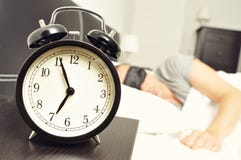 Alarm clock and young man sleeping in bed with a sleep mask stock images Alarm clock and young man sleeping in bed with a sleep mask stock images