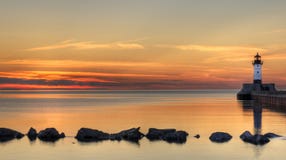 Alba del faro del grande lago con le rocce fotografia stock libera da diritti Alba del faro del grande lago con le rocce fotografia stock libera da diritti