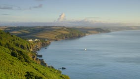 Alba sopra la baia di inizio vicino alla casa leggera che guarda lungo la costa verso le sabbie di Slapton e di Beesands con il r fotografie stock Alba sopra la baia di inizio vicino alla casa leggera che guarda lungo la costa verso le sabbie di Slapton e di Beesands con il r fotografie stock