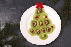 Albero di Natale fatto dal kiwi e dal melograno, idea creativa per i piatti festivi del nuovo anno e di Natale immagine stock Albero di Natale fatto dal kiwi e dal melograno, idea creativa per i piatti festivi del nuovo anno e di Natale immagine stock