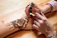 Alheña de la pintura del artista del mehendi de la mujer joven en la mano fotos de archivo Alheña de la pintura del artista del mehendi de la mujer joven en la mano fotos de archivo