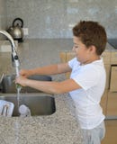 Alho de lavagem da criança na cozinha fotos de stock Alho de lavagem da criança na cozinha fotos de stock