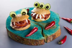 Alimento do partido de Dia das Bruxas Os Hamburger do monstro fecham-se acima com pimentas de pimentão vermelho foto de stock Alimento do partido de Dia das Bruxas Os Hamburger do monstro fecham-se acima com pimentas de pimentão vermelho foto de stock