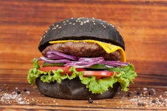 Aliments de préparation rapide, hamburger noir appétissant, admirablement présenté sur un fond en bois image stock Aliments de préparation rapide, hamburger noir appétissant, admirablement présenté sur un fond en bois image stock