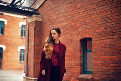 All'aperto ritratto di modo di stile di vita della ragazza castana Cappotto rosso alla moda d'uso Camminando alla via della città immagine stock All'aperto ritratto di modo di stile di vita della ragazza castana Cappotto rosso alla moda d'uso Camminando alla via della città immagine stock