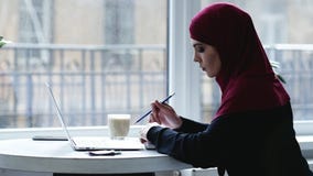 All'interno metraggio di bella ragazza musulmana con hijab sulla sua testa che scrive qualcosa a macchina e poi che scrive qualco stock footage All'interno metraggio di bella ragazza musulmana con hijab sulla sua testa che scrive qualcosa a macchina e poi che scrive qualco stock footage