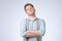 Allvarlig självisk man med vikta armar och hängslen som poserar på studion fotografering för bildbyråer Allvarlig självisk man med vikta armar och hängslen som poserar på studion fotografering för bildbyråer